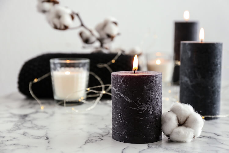 Image shows a marble worktop with black and white candles and fairy lights.