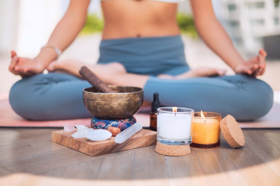 What is a chakra wand? | Woman in lotus pose with crystal wands and candles in front of her.